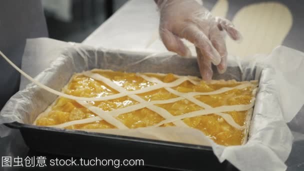 人准备水果橙色柠檬馅饼在厨房桌上, 最后的装饰在手套, 餐厅厨房烘焙产品工厂